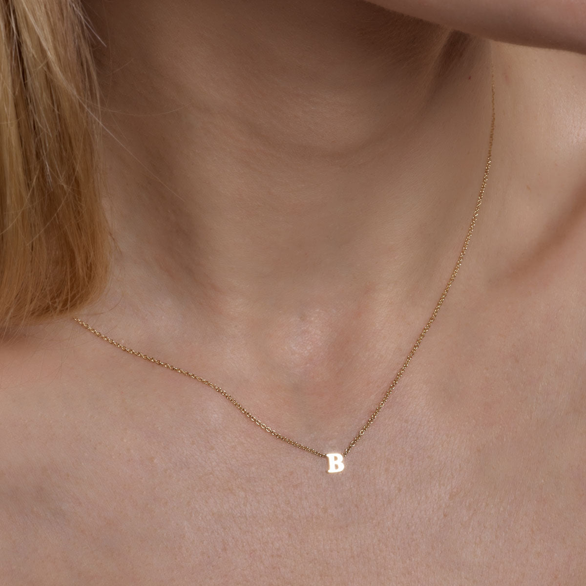 Gold initial necklace on woman, showcasing style and personalized charm.