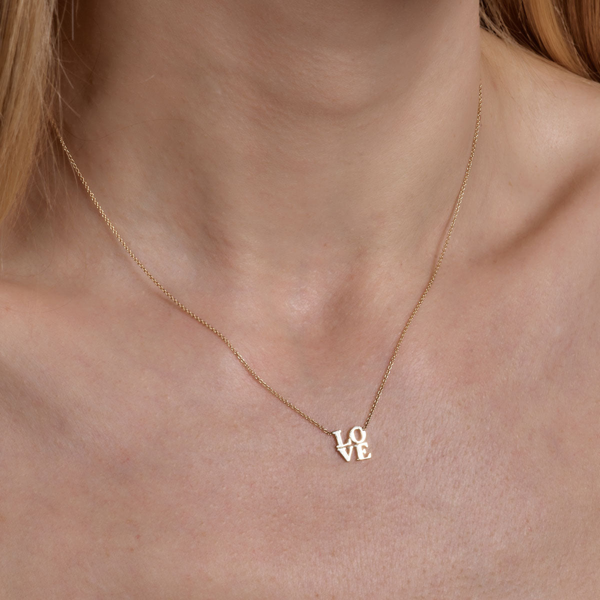 Gold LOVE word necklace - elegant scripted pendant on woman's neck